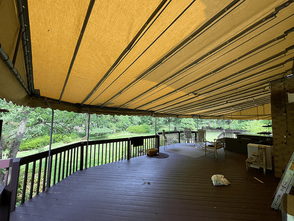 tan canvas awning installed over a large back deck
