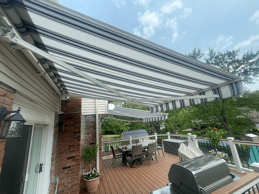 grey and white retractable awning installed on a brick home over the rear deck