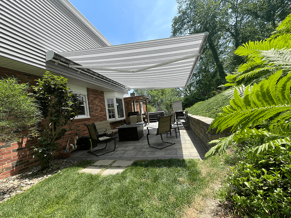 another view of grey and white retractable awning installed over a paver patio