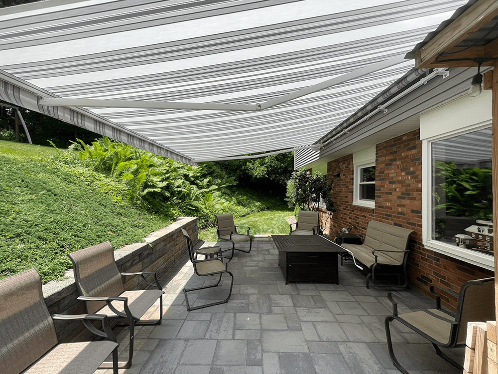 grey and white retractable awning installed over a paver patio