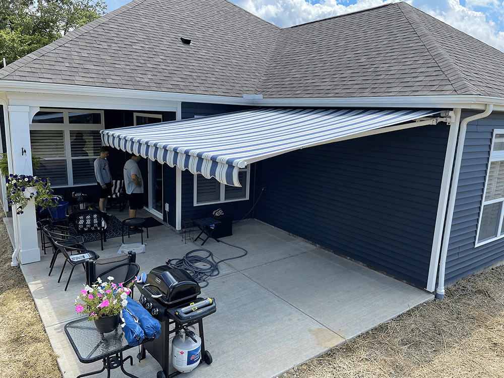 blu eand white striped retractable awning installed over a concrete patio